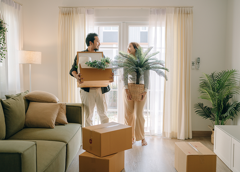 Two people smiling holding moving boxes in home 两个人微笑着在家里拿着移动的箱子